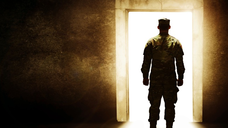 Back of uniformed soldier standing open doorway