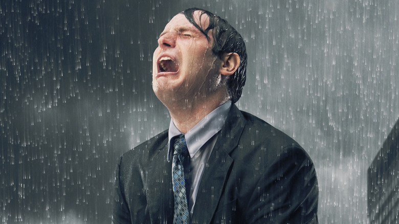 Crying man soaked in rain